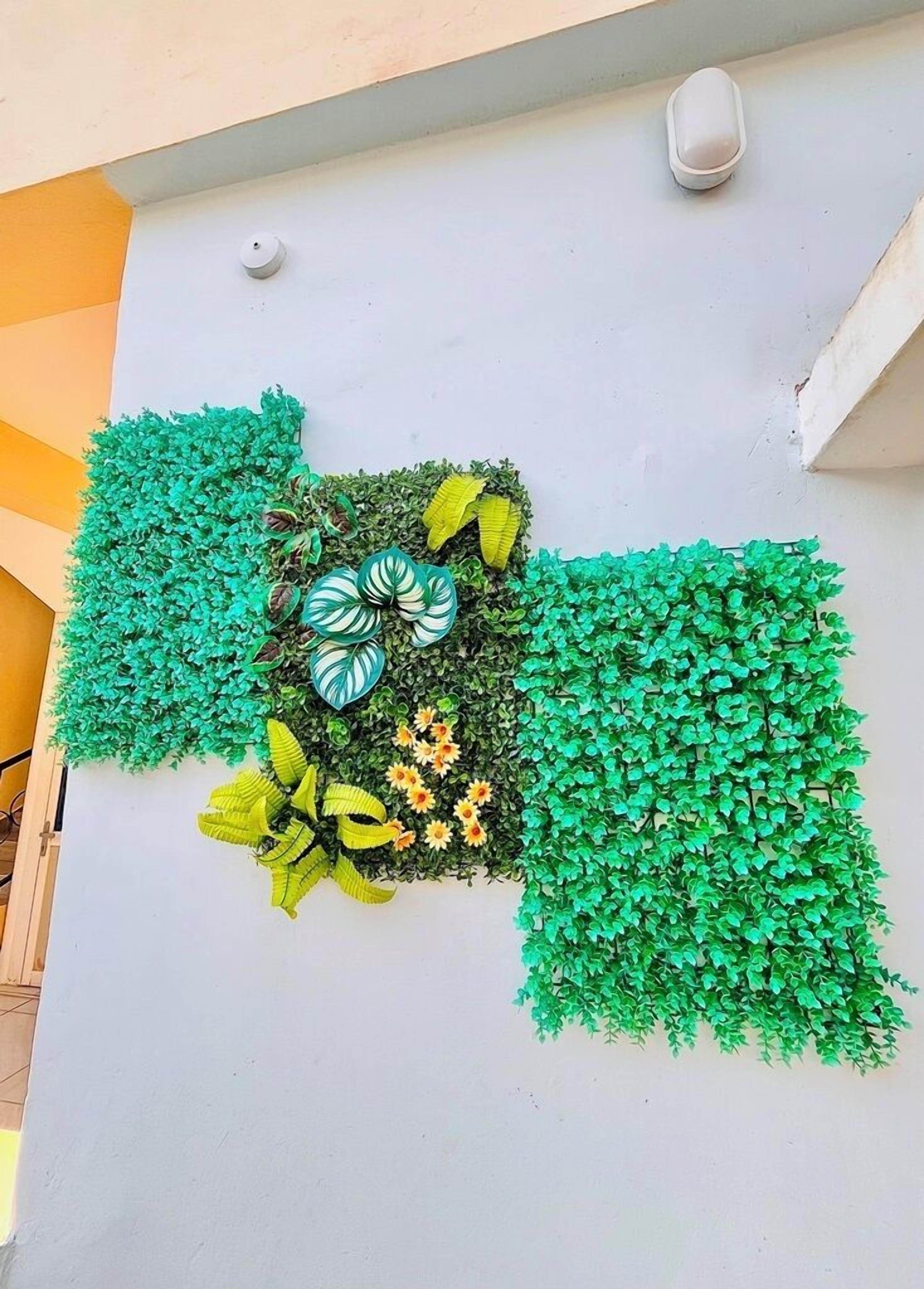 Un mur orné de feuilles et de fleurs artificielles vertes.