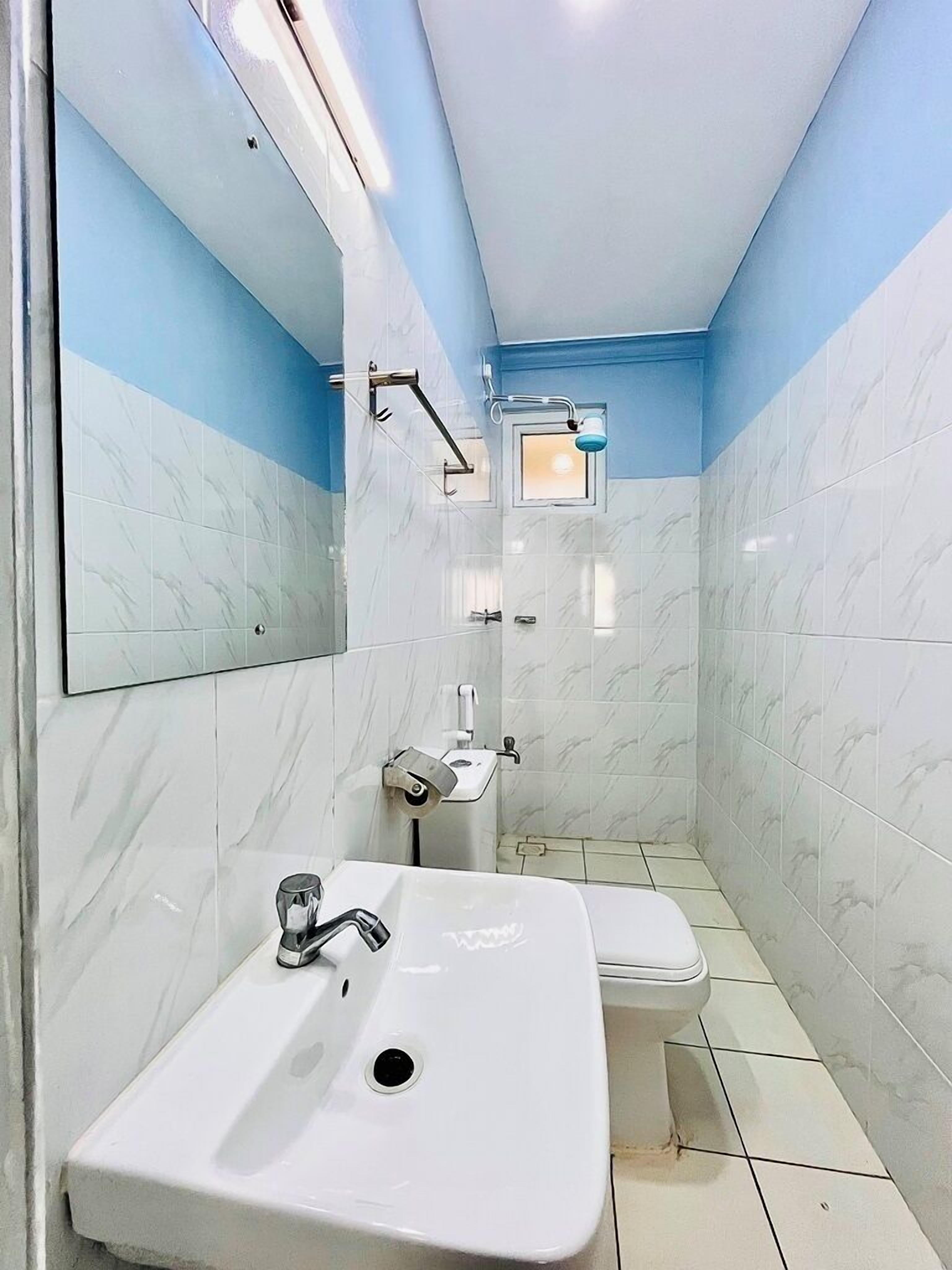 A bathroom with a white sink, a mirror, a toilet, and a shower area.