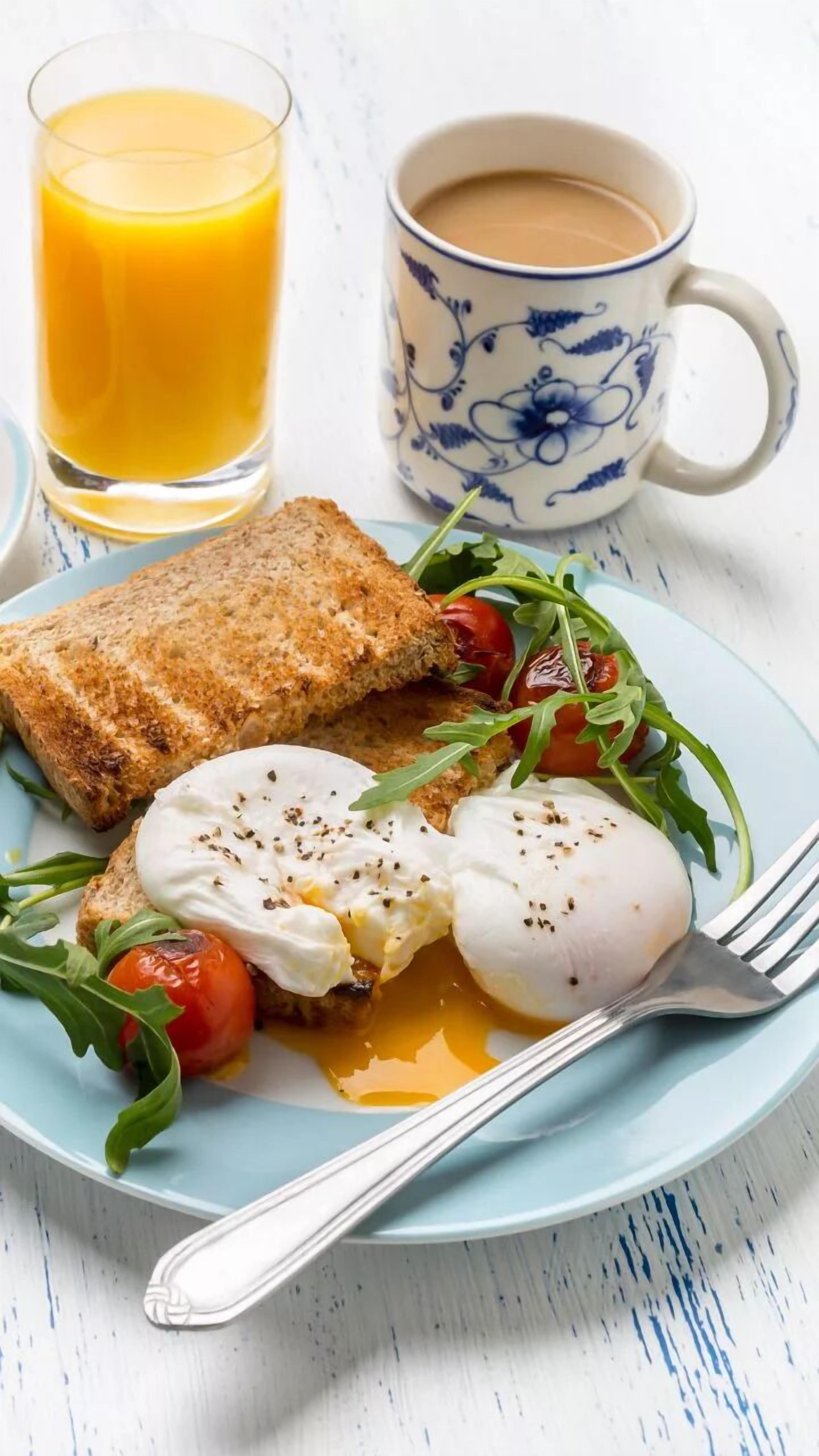 A plate with toast, poached eggs, tomatoes, and greens, accompanied by a glass of orange juice and a cup of coffee.