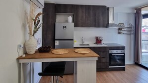 Eine moderne Küche mit Kochinsel, dunklen Holzschränken, einem Einbauofen und einem großen Fenster mit Vorhängen.