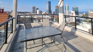 Terraza en la azotea con pérgola, una mesa y sillas.