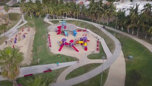 An aerial view of a playground with various play structures, surrounded by palm trees and a curved pathway. - Cabo Villa for 20 w Ocean Views Pool Hot tub (San José del Cabo)