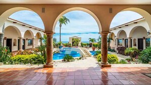 A covered outdoor area with a pool, arches, and a view of the ocean. - Cabo Villa for 20 w Ocean Views Pool Hot tub (San José del Cabo)