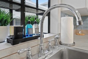A modern kitchen with a stainless steel sink, a soap dispenser, and a paper towel holder. - Waterfront Serenity Steps to Beach Fire Pit BBQ (St. Augustine)