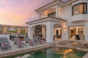 A modern villa with a pool, outdoor seating, and a dining area.