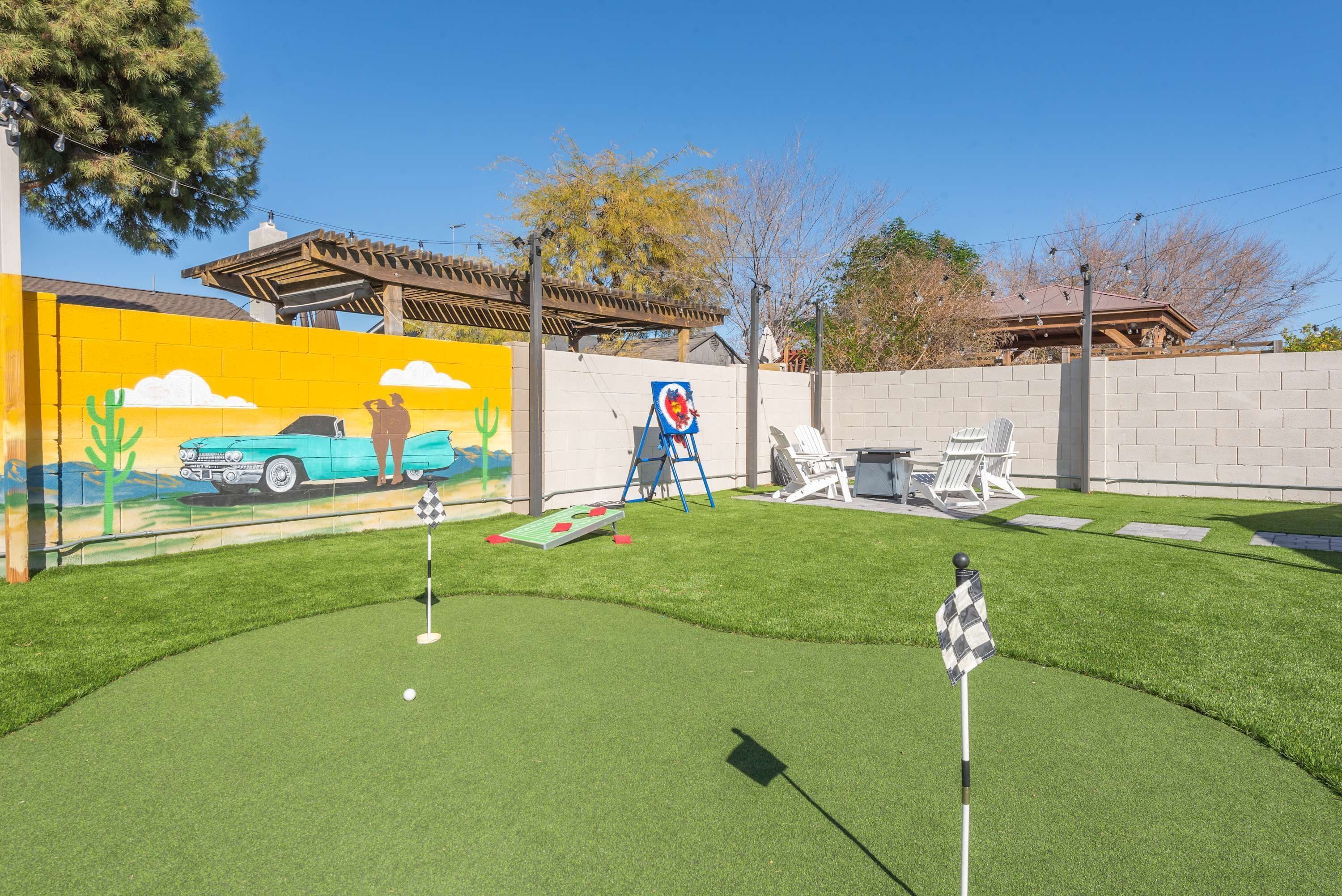 En baghave med putting green, mural og patio.