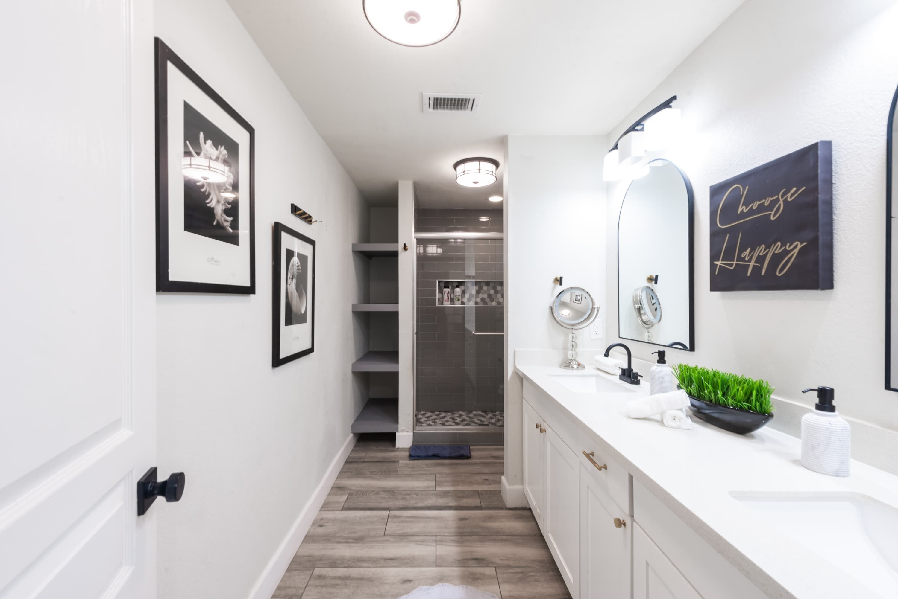 A modern bathroom with a white vanity, a large mirror, and a "Choose Happy" sign.