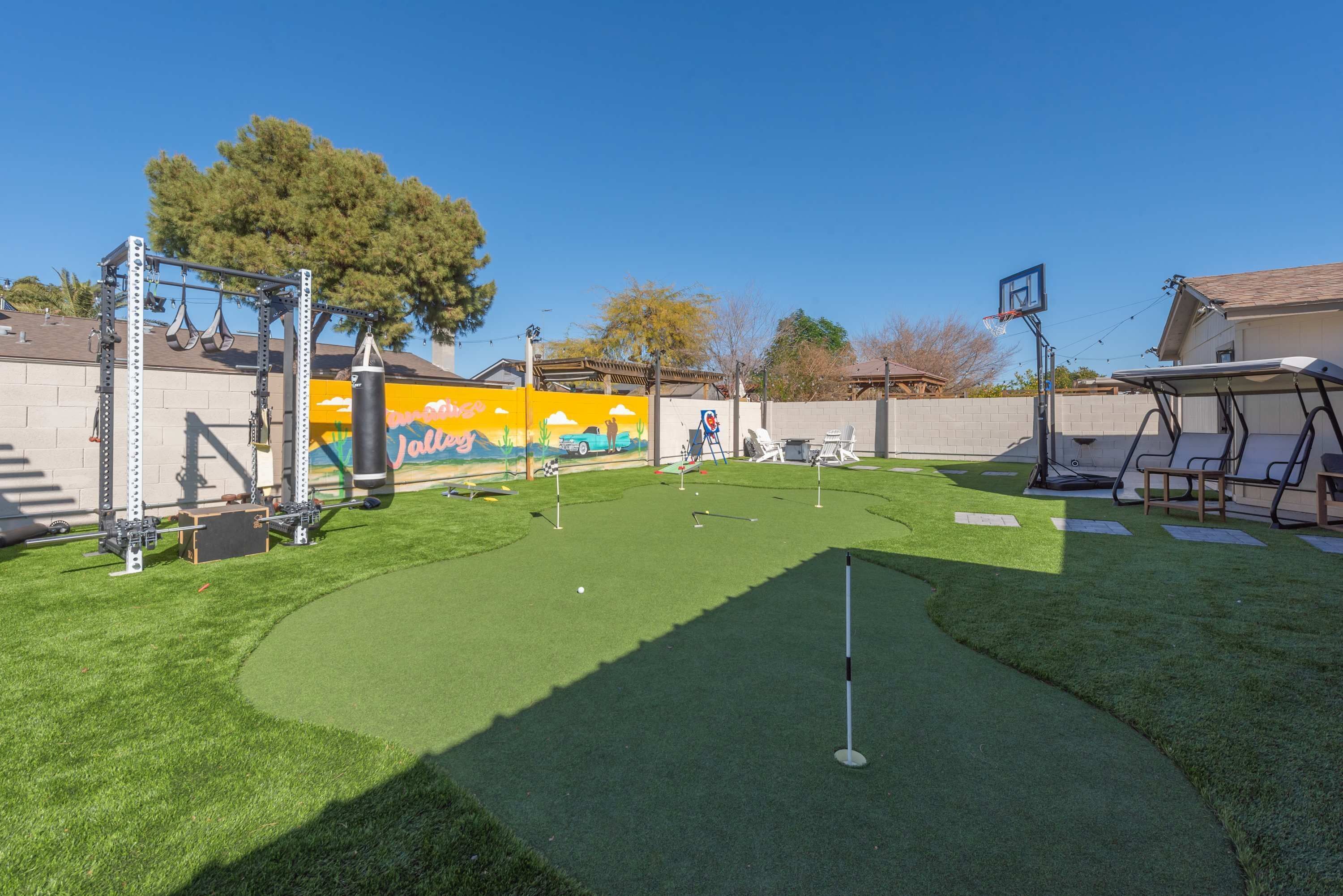 Ein Garten mit Putting Green, Basketballkorb und Kletterwand.