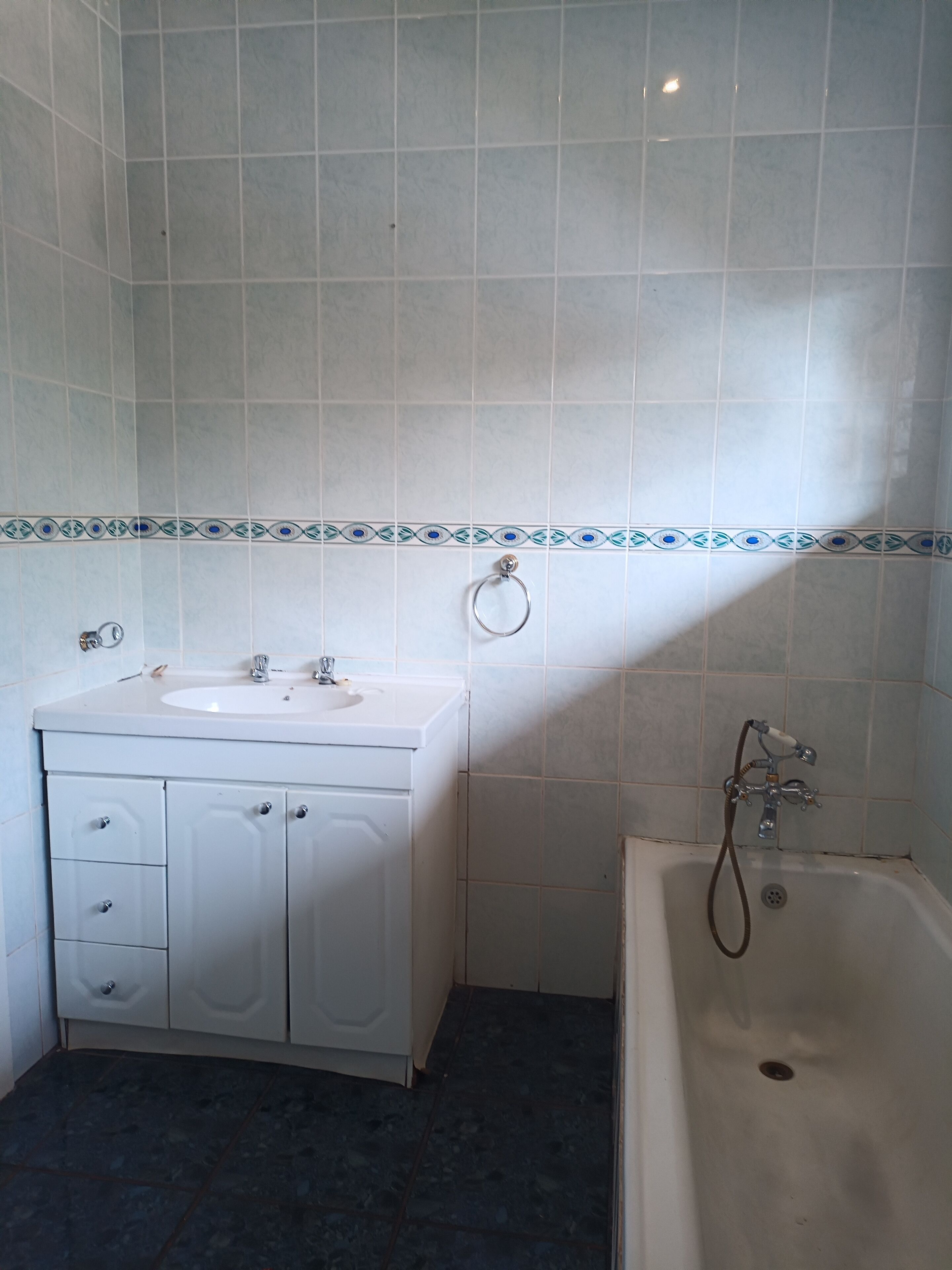 A bathroom with a white sink, cabinet, and bathtub.