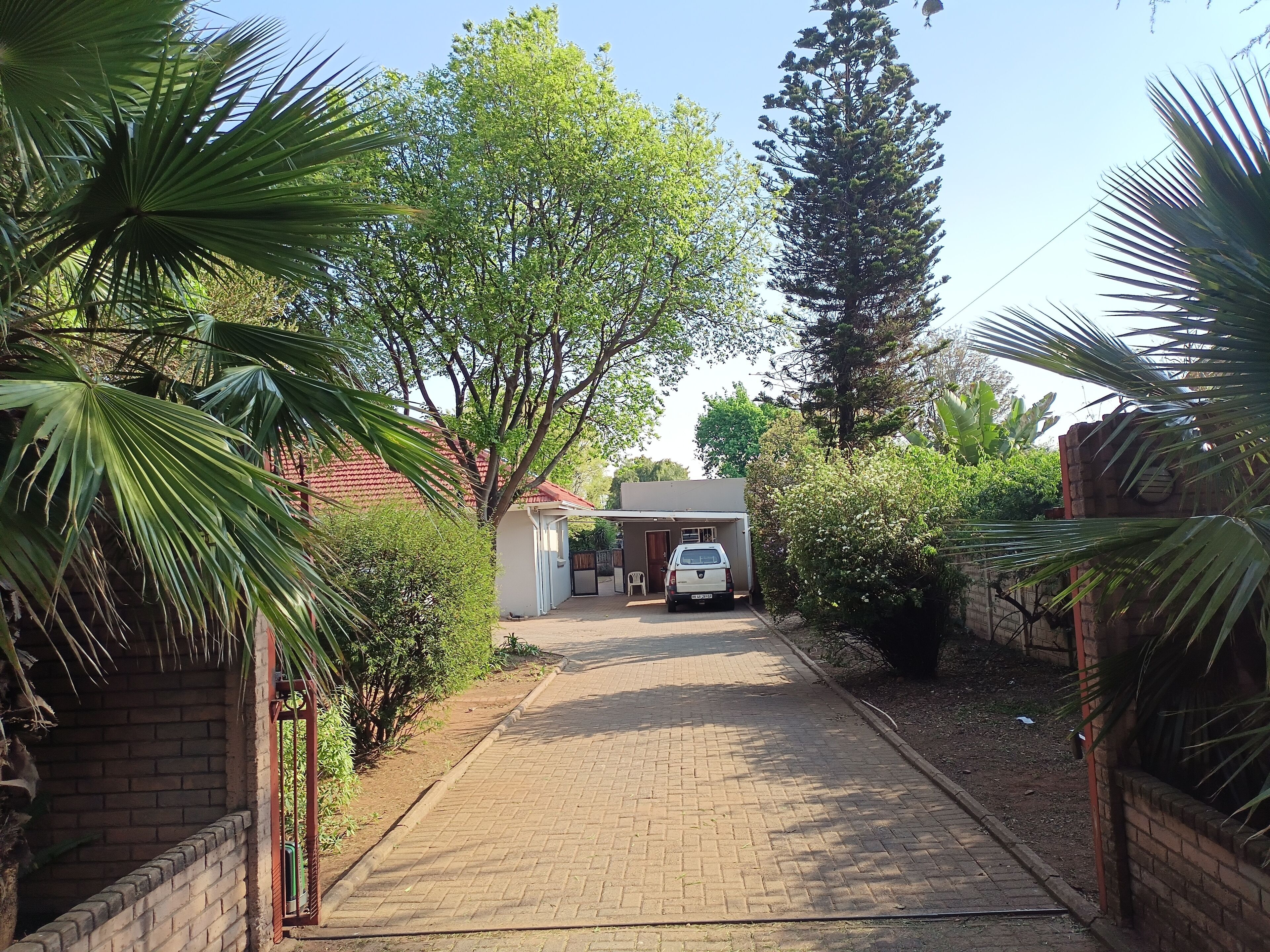 A paved driveway leading to a house with a car parked in front.