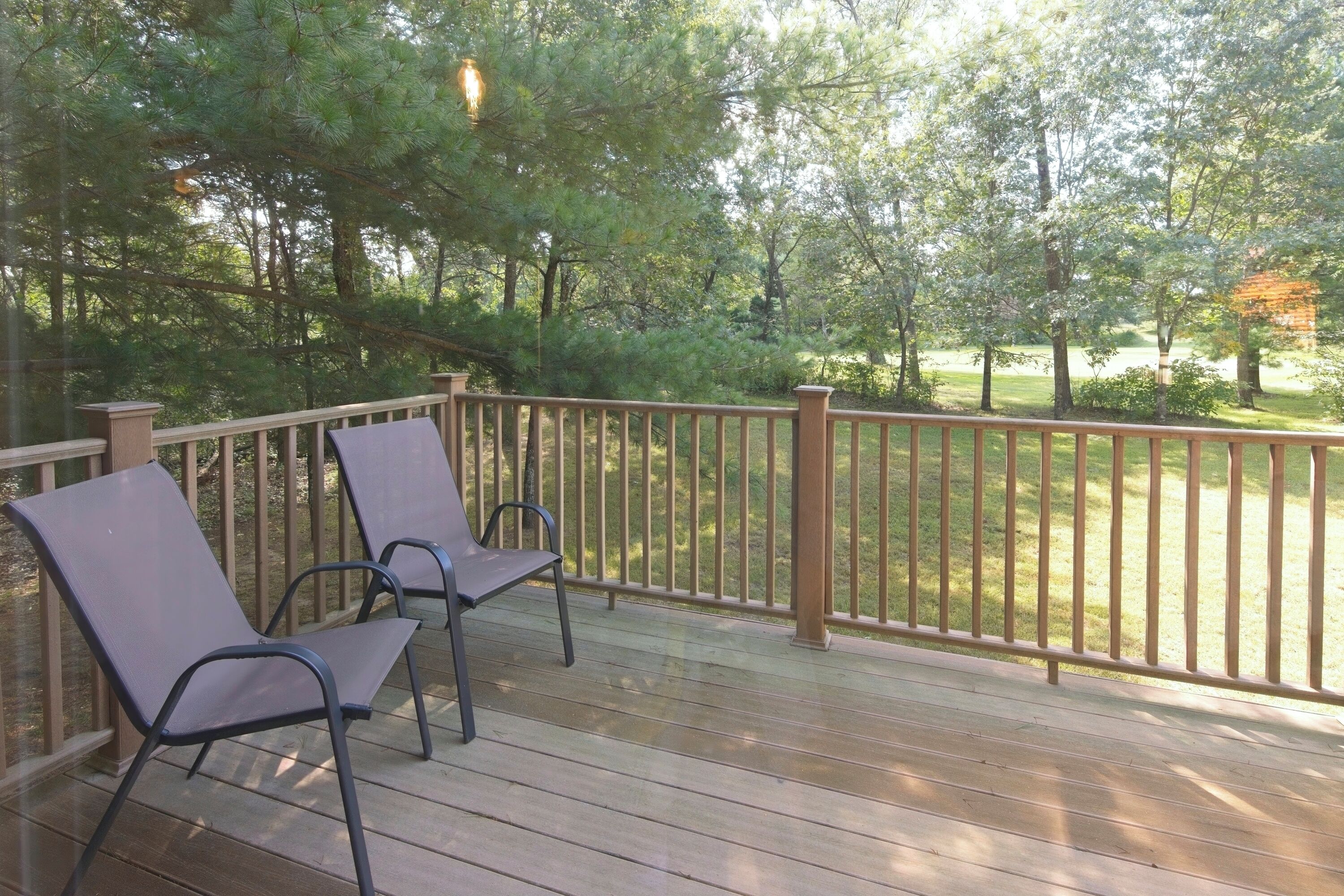 Eine Holzterrasse mit zwei Metallstühlen und einem Hollergeländer.