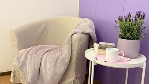 A corner of a room with a beige armchair, a small white table with a potted plant, a book, and a mug. - Romantic Loft in the historic center of Lucca, ideal for visiting the city on foot (Lucca)