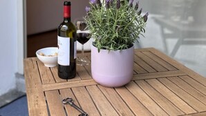 A wooden table with a bottle of wine, a glass, and a potted plant with purple flowers. - Romantic Loft in the historic center of Lucca, ideal for visiting the city on foot (Lucca)