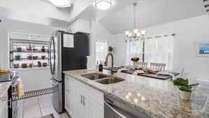 A modern kitchen with granite countertops, stainless steel appliances, and a dining area with a chandelier.