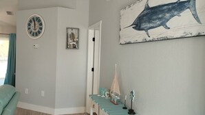 Una habitación con un reloj, un cuadro con motivos náuticos, un pequeño modelo de barco y una cama.