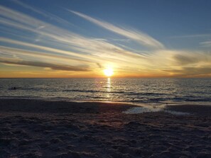 A beach with the sun setting over the ocean, creating a calm and serene atmosphere.