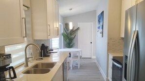 Una cocina moderna con un lavamanos de acero inoxidable, una cafetera y un refrigerador.