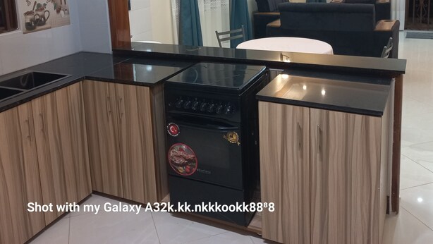 Una cocina moderna con encimera negra, armarios de madera y estufa empotrada.