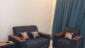 Una sala de estar moderna con dos sofás y una mesita de centro, con detalles de madera y cojines estampados.