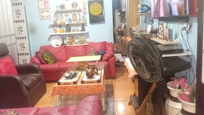 A living room with a red sofa, a coffee table, and a TV mounted on the wall. - COP 30 SOLAR MOON (Belém)