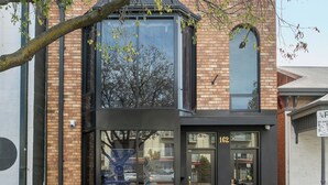 A modern building with a glass facade, a brick exterior, and a black entrance. - Cozy Stays - Private Rooms (Adelaide)
