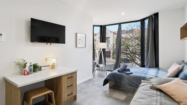 A modern bedroom with a bed, desk, and TV. - Cozy Stays - Private Rooms (Adelaide)