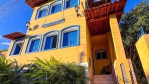 A two-story building with a yellow facade and blue-framed windows. - Pousada Lavramor (Lençóis)