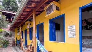 A yellow building with blue-framed windows and a hammock on the porch. - Pousada Lavramor (Lençóis)