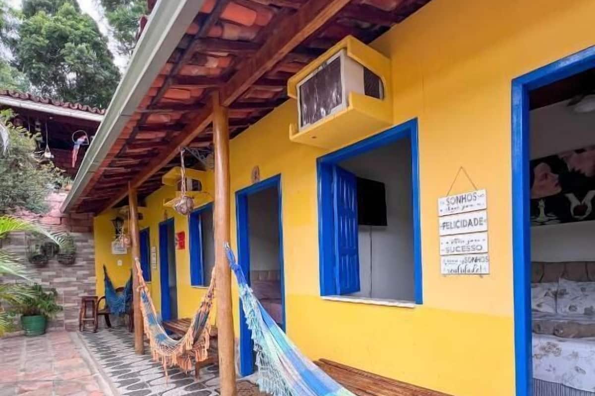 A yellow building with blue-framed windows and a hammock on the porch.