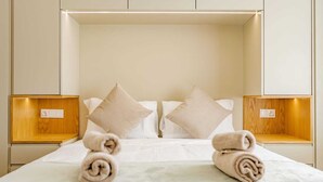 Un lit double bien fait, avec deux oreillers, une tête de lit en bois et deux tables de chevet avec des lampes.