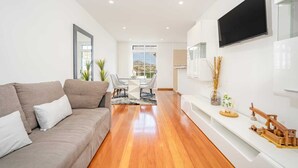 Un salon moderne comprenant un canapé, un coin repas et un téléviseur fixé au mur.