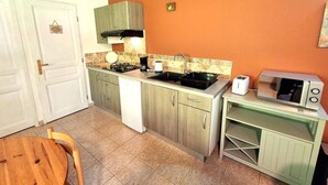 A compact kitchen with a white refrigerator, a stove, a microwave, and a sink.