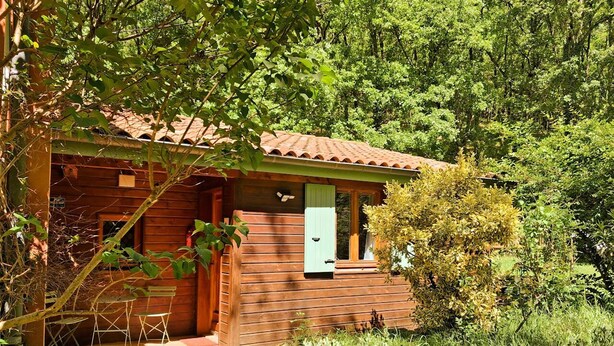 A wooden cabin with a tiled roof, a small porch, and a door with a window.