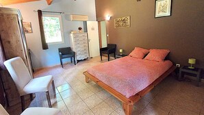 A bedroom with a bed, a chair, a dresser, and a desk.
