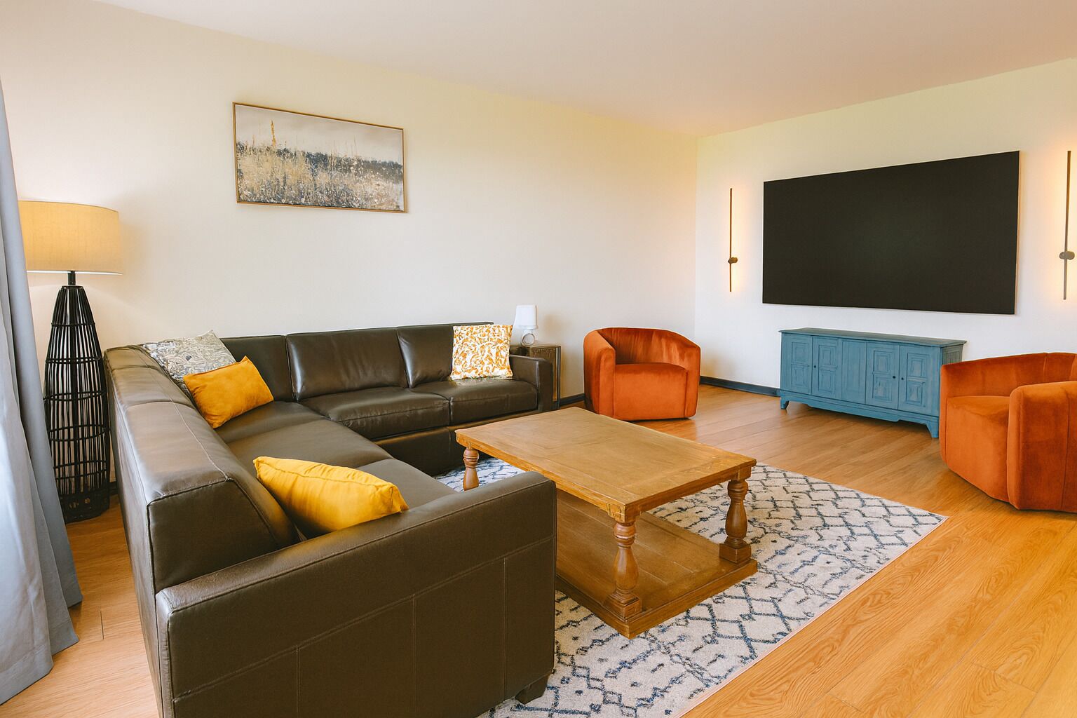 Una sala de estar moderna con un sofá seccional, una mesa de centro, un televisor y un armario azul.
