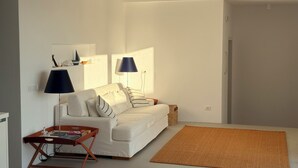 A modern living room with a white sofa, two floor lamps, a wooden coffee table, and a woven rug. - 4-Bedroom Villa in Milos, Seaview and Sunset view, Private Pools (Milos)