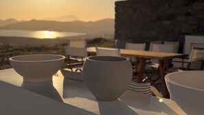 A table with bowls and chairs, overlooking a body of water and mountains. - 4-Bedroom Villa in Milos, Seaview and Sunset view, Private Pools (Milos)