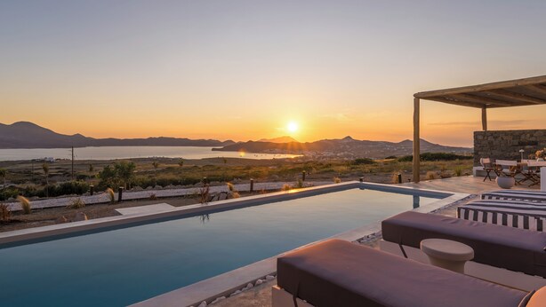 A poolside area with lounge chairs and a view of the sunset over the sea. - 4-Bedroom Villa in Milos, Seaview and Sunset view, Private Pools (Milos)