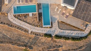 An aerial view of a resort with multiple swimming pools, a covered area, and a stone pathway. - 4-Bedroom Villa in Milos, Seaview and Sunset view, Private Pools (Milos)