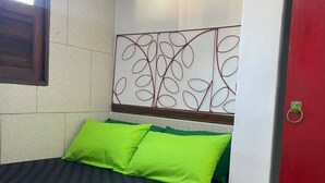A small, compact room with a bed, a window, and a red door. - Compact Tiny House Bambuzal (Paty do Alferes)
