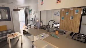 A modern kitchen with a central island, bar stools, a sink, and a stove. - Mobilhome cap ferret (Lège-Cap-Ferret)