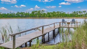 A wooden dock extending into a calm lake with a clear sky and a line of trees in the background. - Point & Paddle
Waterfront Retreat @Alligator Point (Alligator Point)