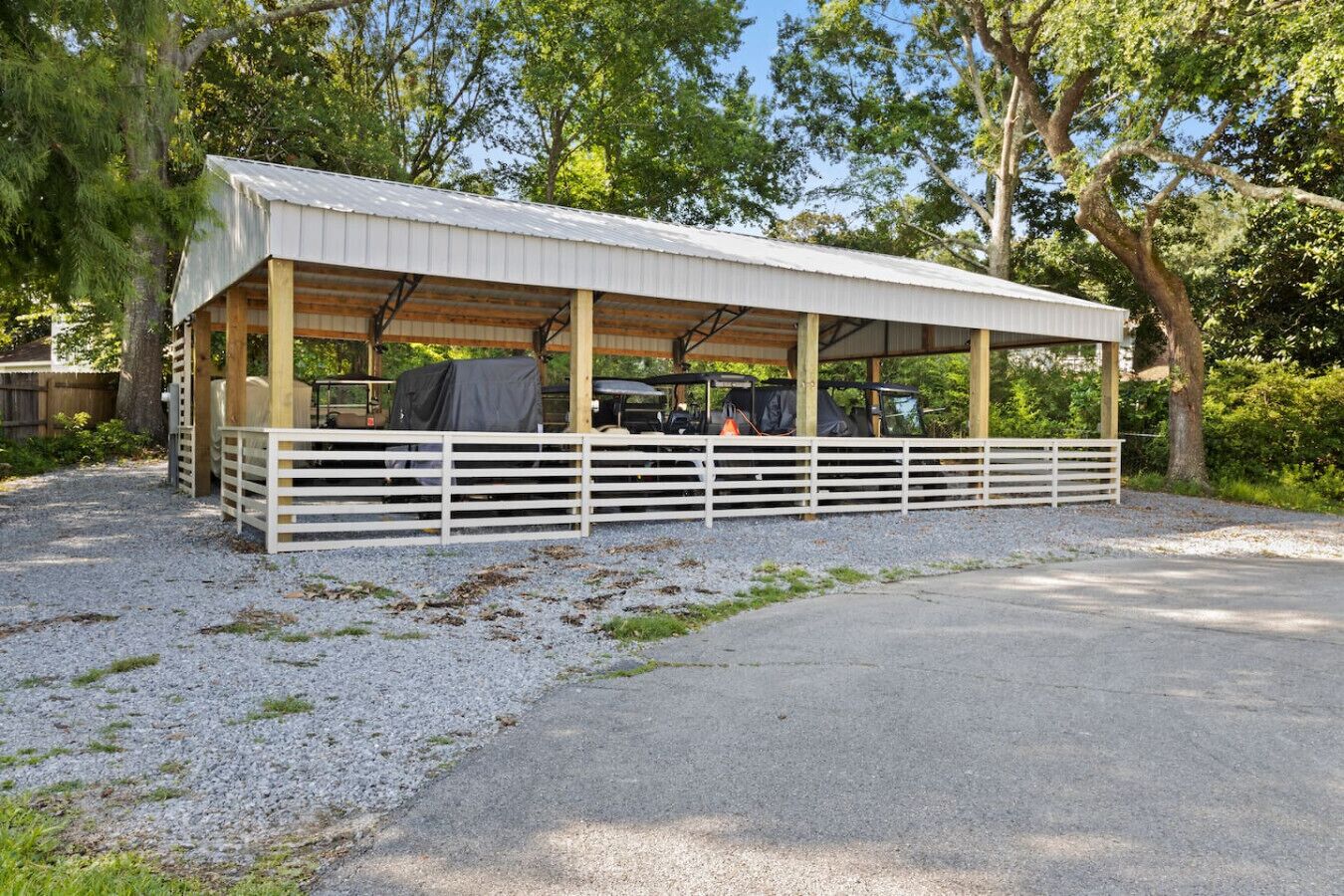 A covered outdoor area with a gravel path leading to a wooden structure with a metal roof.