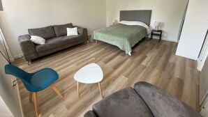 Un dormitorio con cama, sofá, sillón y mesita de noche.