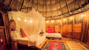 A room with a bed under a mosquito net, wooden walls, and a thatched roof. - Salvia Madre Hotel Boutique (Santa Marta)