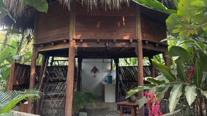 A wooden structure with a thatched roof, surrounded by lush greenery and a stone wall. - Salvia Madre Hotel Boutique (Santa Marta)