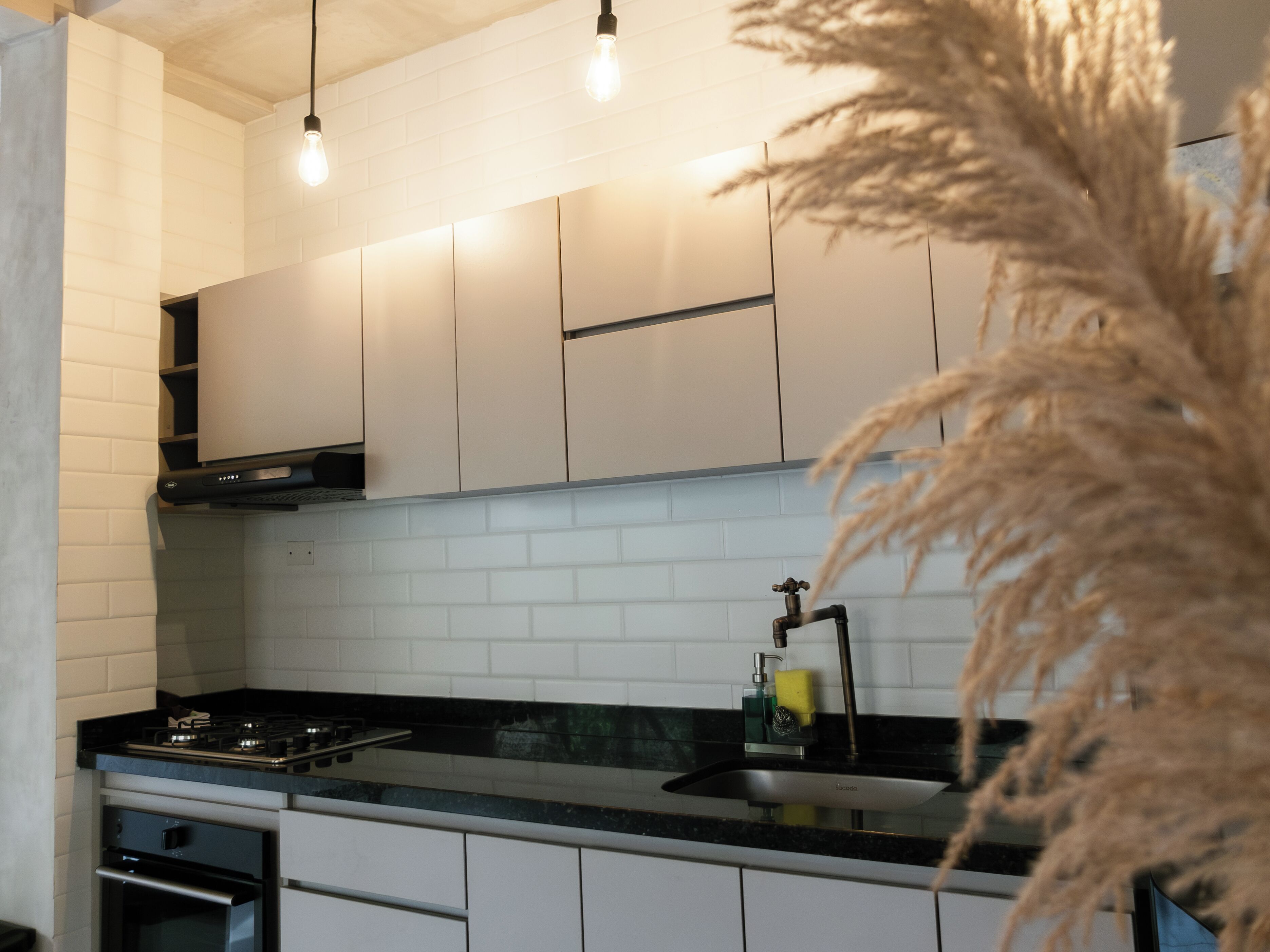 A modern kitchen with white cabinets, a black countertop, and a stainless steel sink.