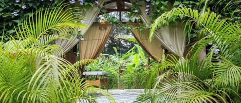 Un exuberante jardín con un banco de madera, un sendero de piedra y una pérgola cubierta de plantas trepadoras y flores.