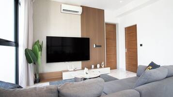 Una sala de estar moderna con una televisión de pantalla plana, una mesa de centro y un sofá.