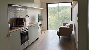 Una cocina moderna con vigas de madera, un ventanal grande y un sofá en la zona de estar contigua.
